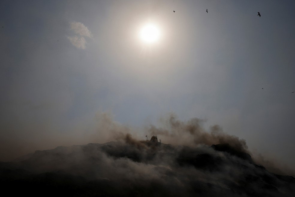 Uma escavadeira tenta conter o fogo criado naturalmente pelo calor na capital indiana de Nova Delhi — Foto: Adnan Abidi/REUTERS