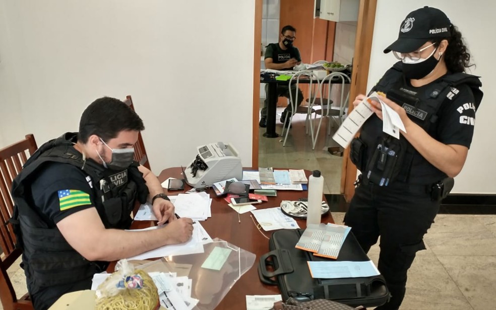 Policiais avaliam talões de cheque e documentos encontrados em casa visitada na Operação Déjà vu — Foto: Reprodução/Polícia Civil