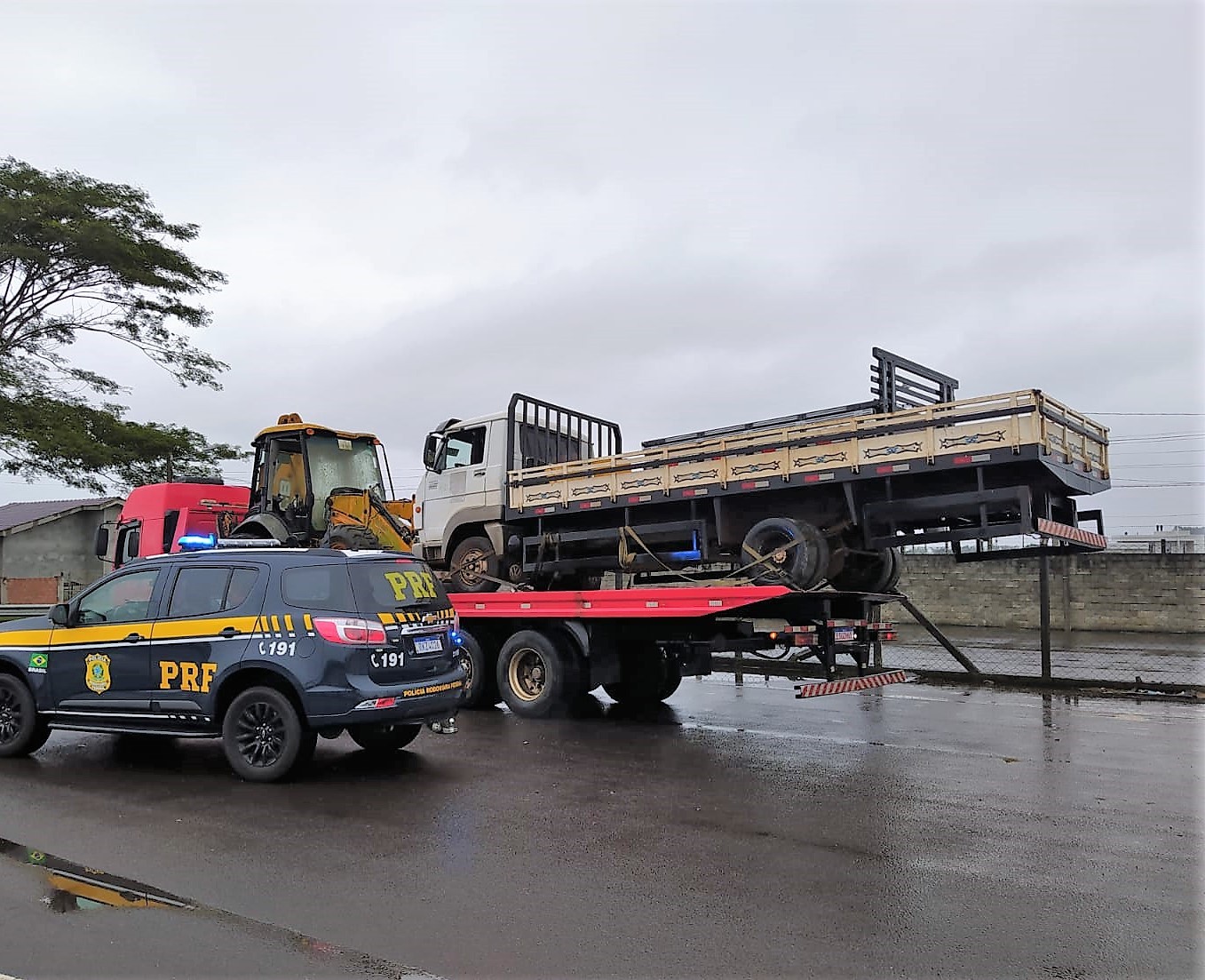 Caminhão é transportado de forma irregular por outro veículo com parte da carroceria para fora; FOTO