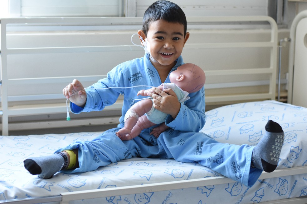 Artur brinca de fazer exames de sangue e de colocar cateter em Murilo, seu boneco — Foto: Camila Mendes/Divulgação Hospital Pequeno Príncipe