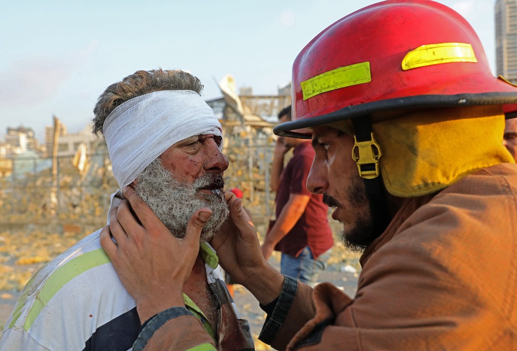 Homem ferido é examinado por um bombeiro perto do local de uma explosão em Beirute — Foto: Anwar Amro/AFP