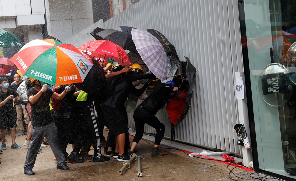 manifestantes usam guarda-chuvas e máscaras para se protegerem do gás disparado pelos policiais durante manifestação em Hong Kong, nesta segunda-feira (1º) — Foto: REUTERS/Tyrone Siu