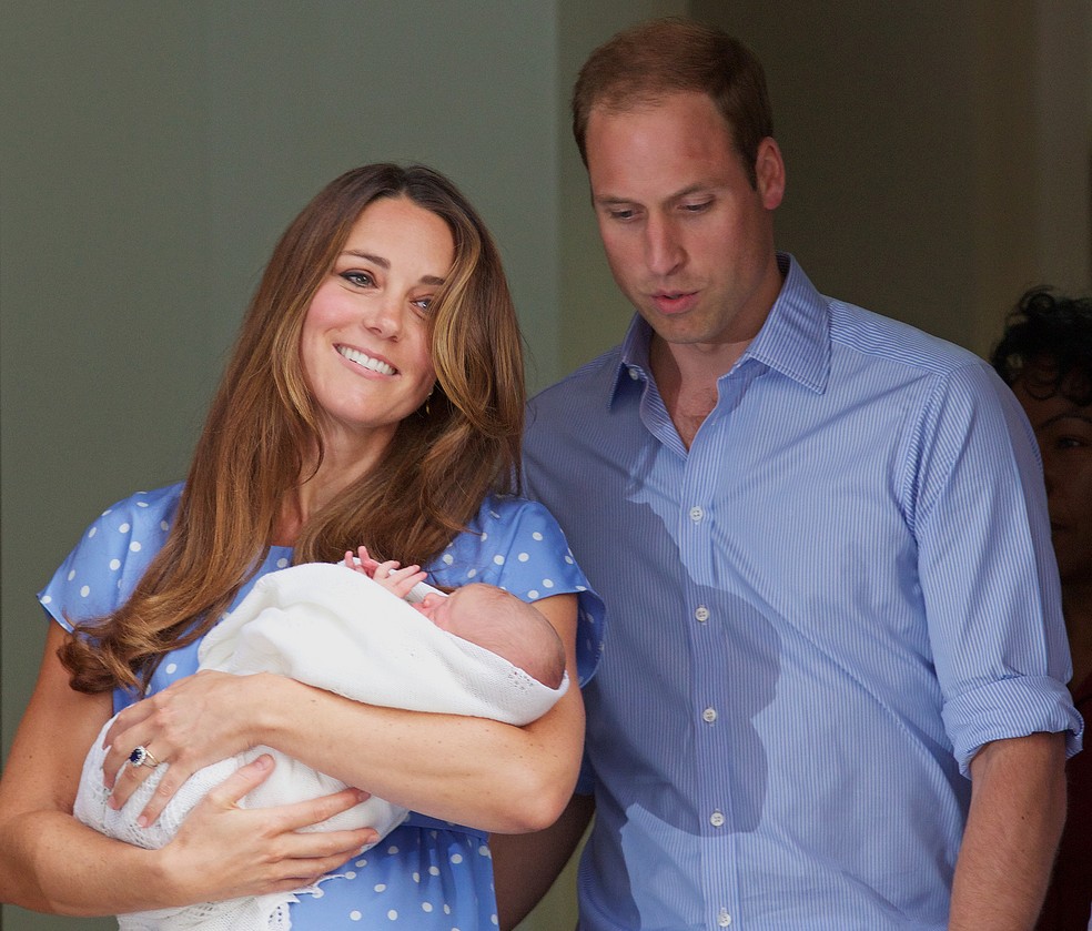 Kate e William deixam o hospital St. Mary's, em Londres, em 2013, com o príncipe George. A aparência da duquesa, de cabelo escovado e maquiagem, causou controvérsias por não retratar, supostamente, uma realidade do pós-parto. — Foto: Andrew Cowie / AFP