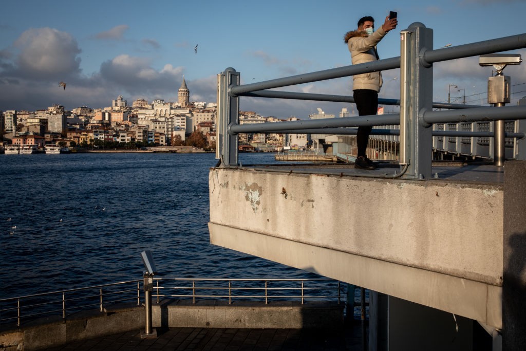 ISTANBUL, TURKEY - DECEMBER 06: A man takes a selfie in front of the Galata Tower during a national weekend coronavirus lockdown on December 06, 2020, in Istanbul, Turkey. Amid surging coronavirus figures, Turkey has reimposed weekday curfews and full wee (Foto: Getty Images)