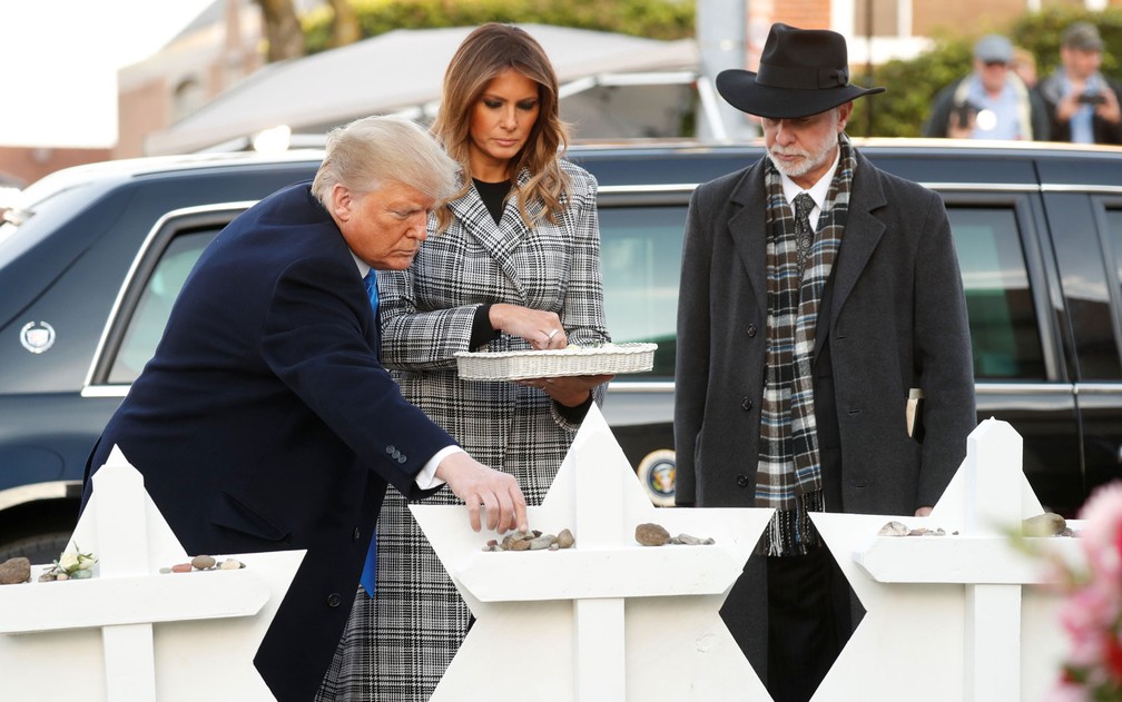 O presidente dos EUA, Donald Trump, deposita uma pedra em homenagem a vítimas de massacre em memorial na Sinagoga Árvore da Vida, acompanhado pela primeira-dama, Melania, e pelo rabino Jeffrey Myers, em Pittsburgh, na terça-feira (30) — Foto: Reuters/Kevin Lamarque