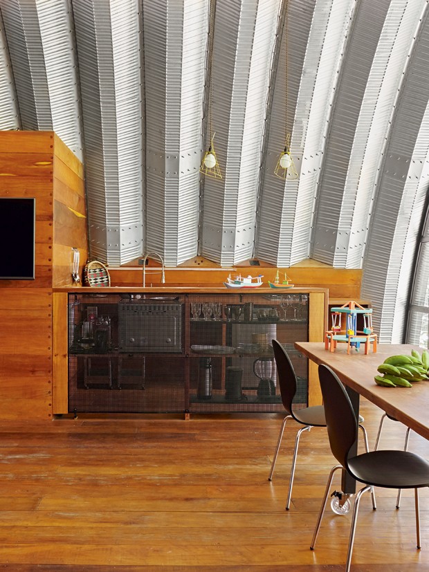 Sala de jantar | O balcão de madeira com tela metálica separa a cozinha equipada com eletrodomésticos de inox e pendentes da Tok&Stok (Foto: Victor Affaro)