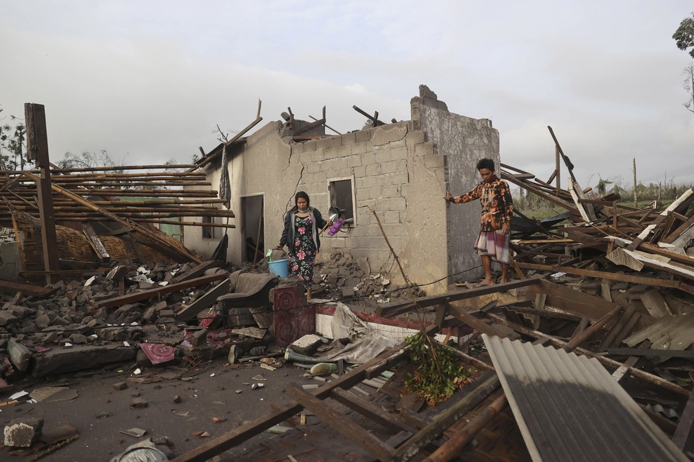 Foto mostra moradores inspecionando danos em sua casa em uma área afetada pela erupção do Monte Semeru, em Lumajang, Java Oriental, Indonésia, neste domingo (5).  — Foto: Trisnadi/AP