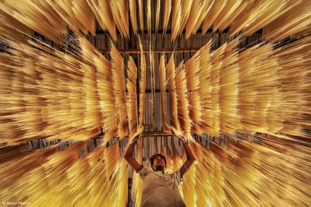 "Um trabalhador está inspecionando se o macarrão de arroz secou corretamente ou não." — Foto: ABDUL MOMIN