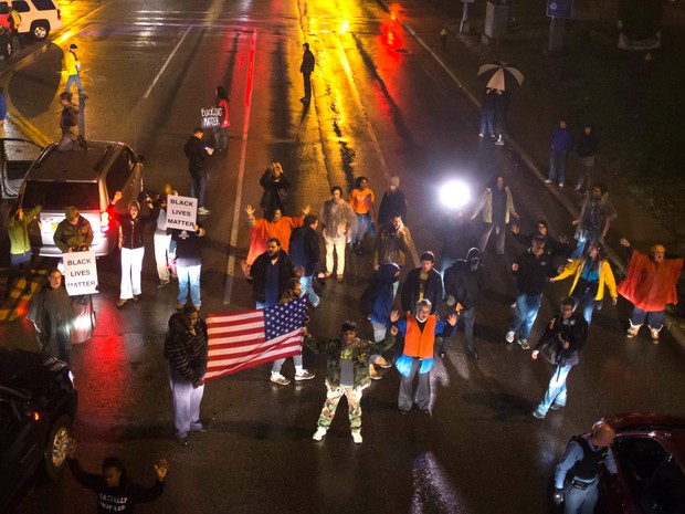 Manifestantes, exigindo a condenação de um policial branco que matou a tiros um adolescente negro desarmado em agosto, param o trânsito durante uma marcha em um subúrbio de St. Louis, Missouri, nos Estados Unidos (Foto: Adrees Latif/Reuters)
