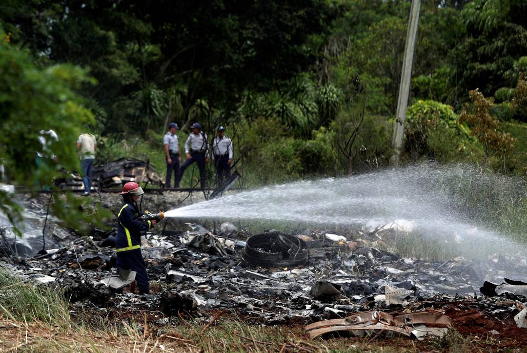 Bombeiro usa mangueira para aguar destroços após desastre aéreo em Havana, Cuba