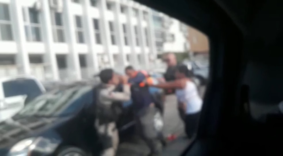 Mulher tenta apartar briga entre policiais militares e funcionário do estacionamento do Fórum de Maceió (Foto: Reprodução)