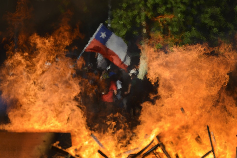 Bandeira do Chile é vista em frente a barricada montada em Santiago durante protesto em 2019 — Foto: Matias Delacroix/AP Photo