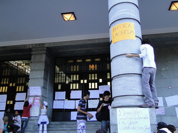 Manifestante coloca cartaz em pilastra da entrada da PBH. (Foto: Pedro Ângelo/G1)