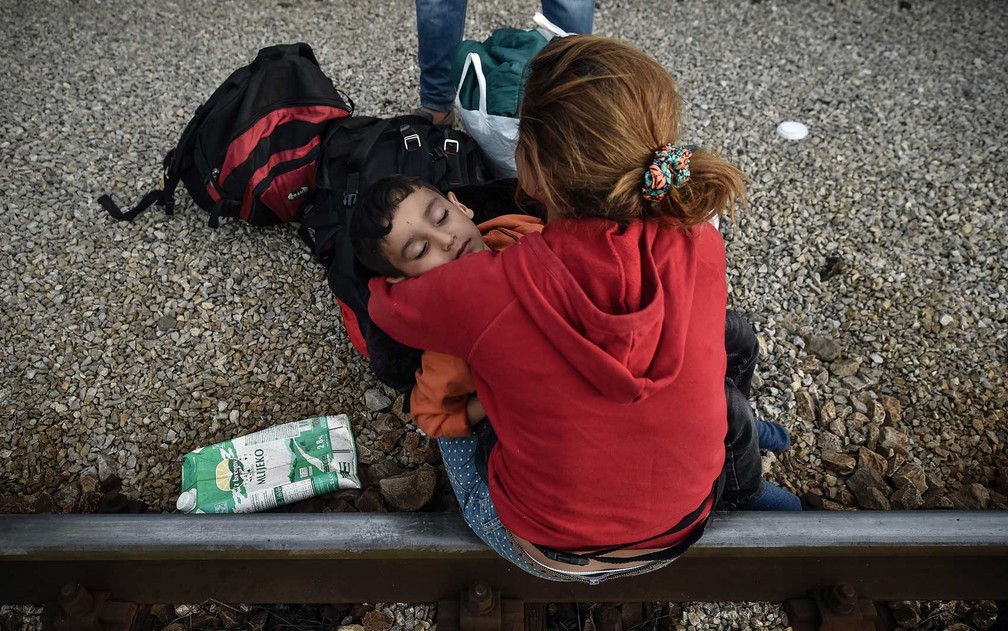 Criança dorme no colo de uma mulher na frente de estação de trem em Dugo Selo, perto de Zagreb. 800 refugiados chegaram ao local (Foto: Andrej Isakovic / AFP Photo)