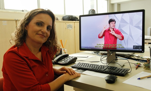 Roteirista do "Primeira Mão", a jornalista Roberta Savedra junto a uma tela que mostra o programa