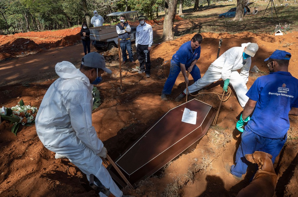 Coveiros com roupas de proteção fazem enterro no cemitério de Vila Formosa, em São Paulo, na quinta-feira (28)  — Foto: Andre Penner/AP