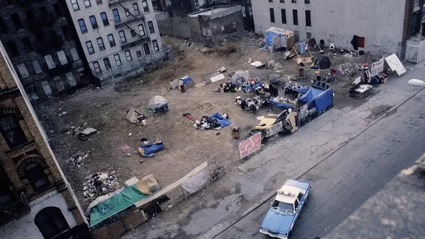 Viatura da polícia observa acampamento de sem-tetos montado em um terreno abandonado no East Village, Nova York, em 1991 (Foto: GETTY IMAGES via BBC)