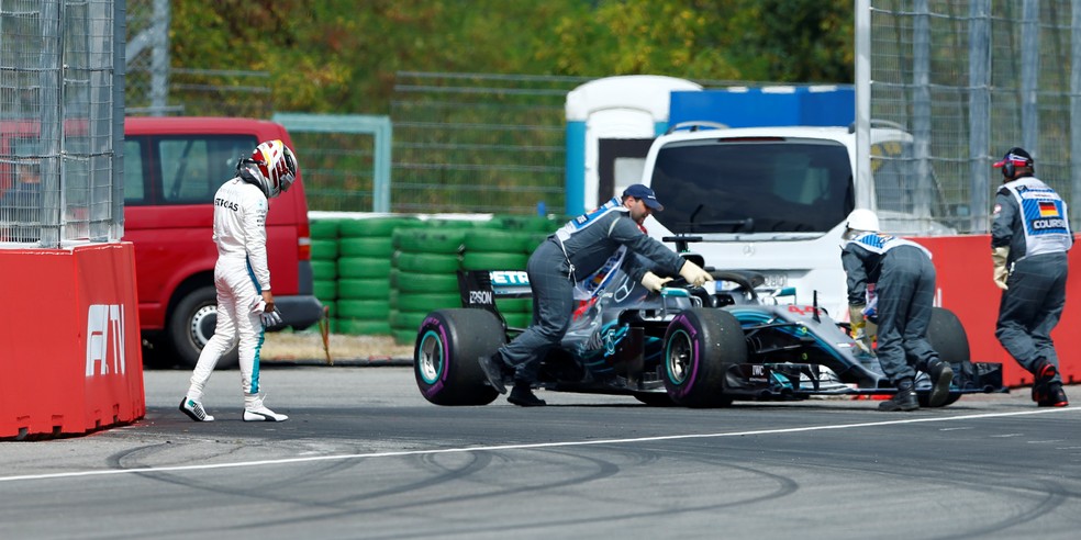 De cabeça baixa, Hamilton acompanha retirada do carro após falha no câmbio (Foto: Reuters)