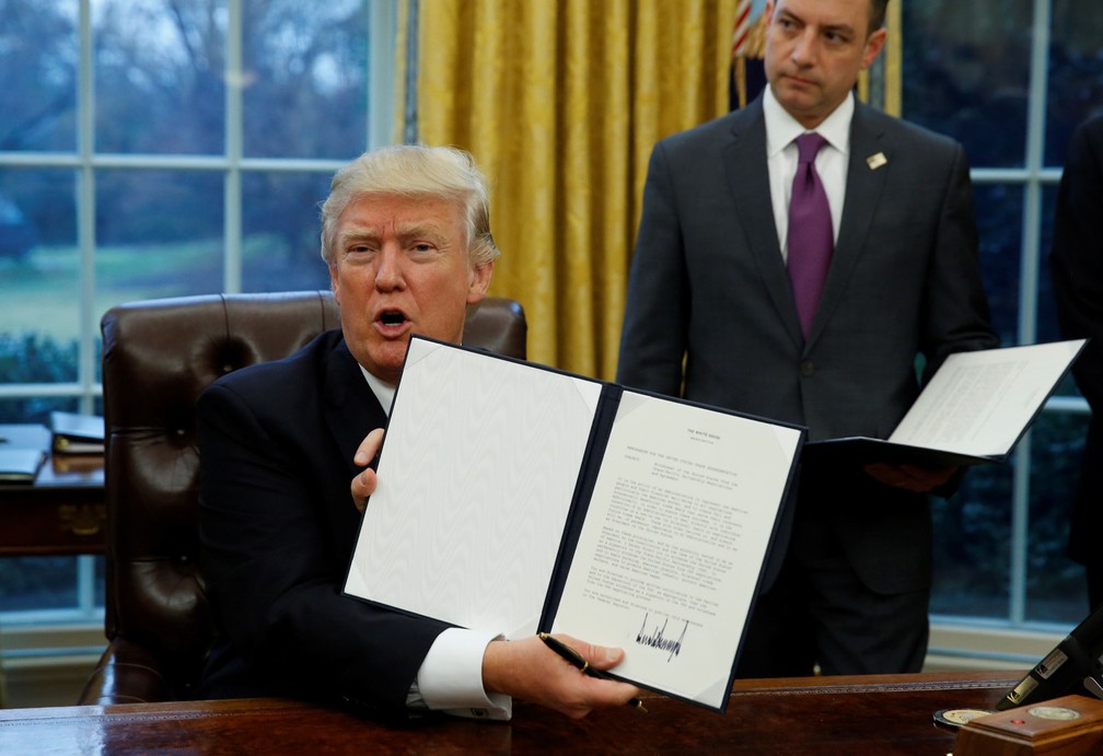 O presidente dos EUA Donald Trump exibe a ordem executiva da retirada dos Estados Unidos do Acordo Transpacífico — Foto: Kevin Lamarque/Reuters