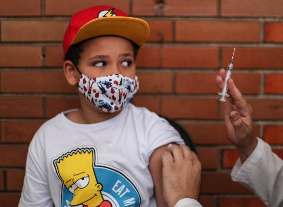 Menino olha para seringa de aplicação da vacina contra Covid-19, na capital paulista — Foto: WERTHER SANTANA/ESTADÃO CONTEÚDO
