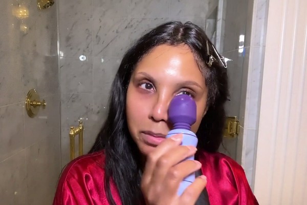 A cantora Toni Braxton usando um vibrador no rosto durante seu tutorial de maquiagem (Foto: YouTube)