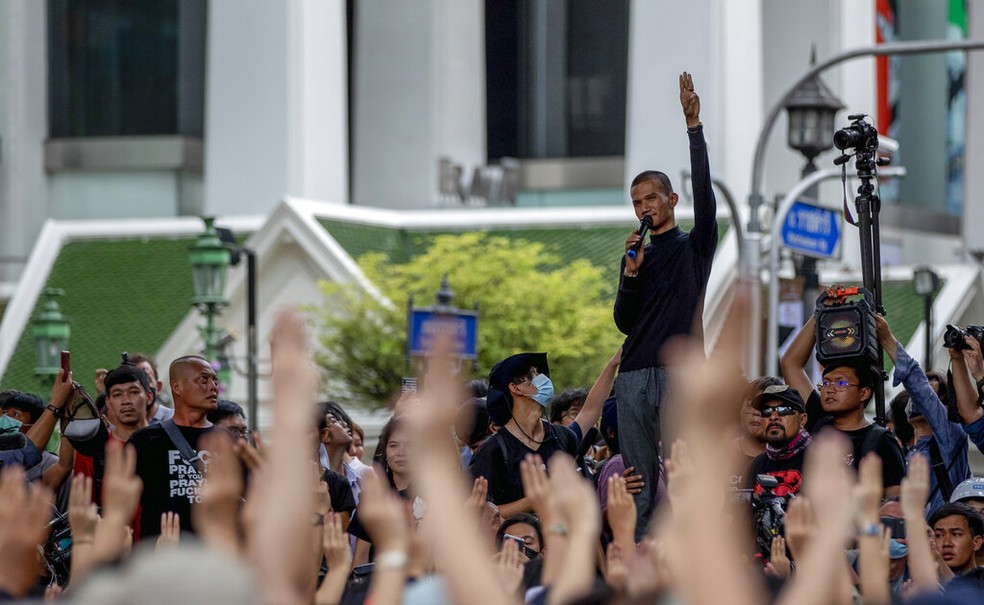 Manifestantes fazem sinal com três dedos erguidos, em desafio ao poder da realeza da Tailândia — Foto: Gemunu Amarasinghe/AP