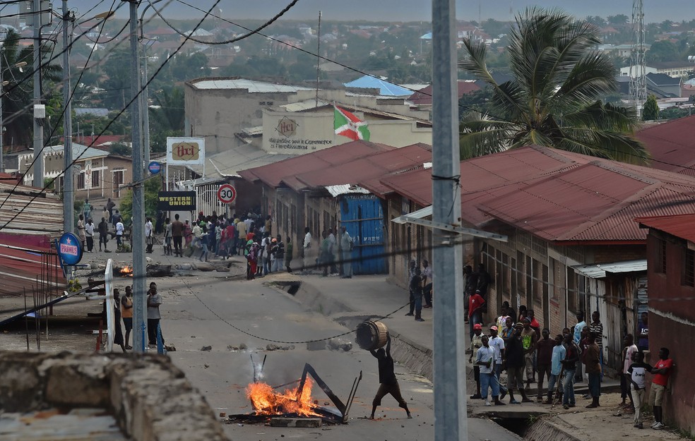 Manifestante contra o terceiro mandato do presidente do Burundi atira objetos sobre uma barricada em chamas no bairro Kinanira na capital Bujumbura (Foto: Carl de Souza/AFP)