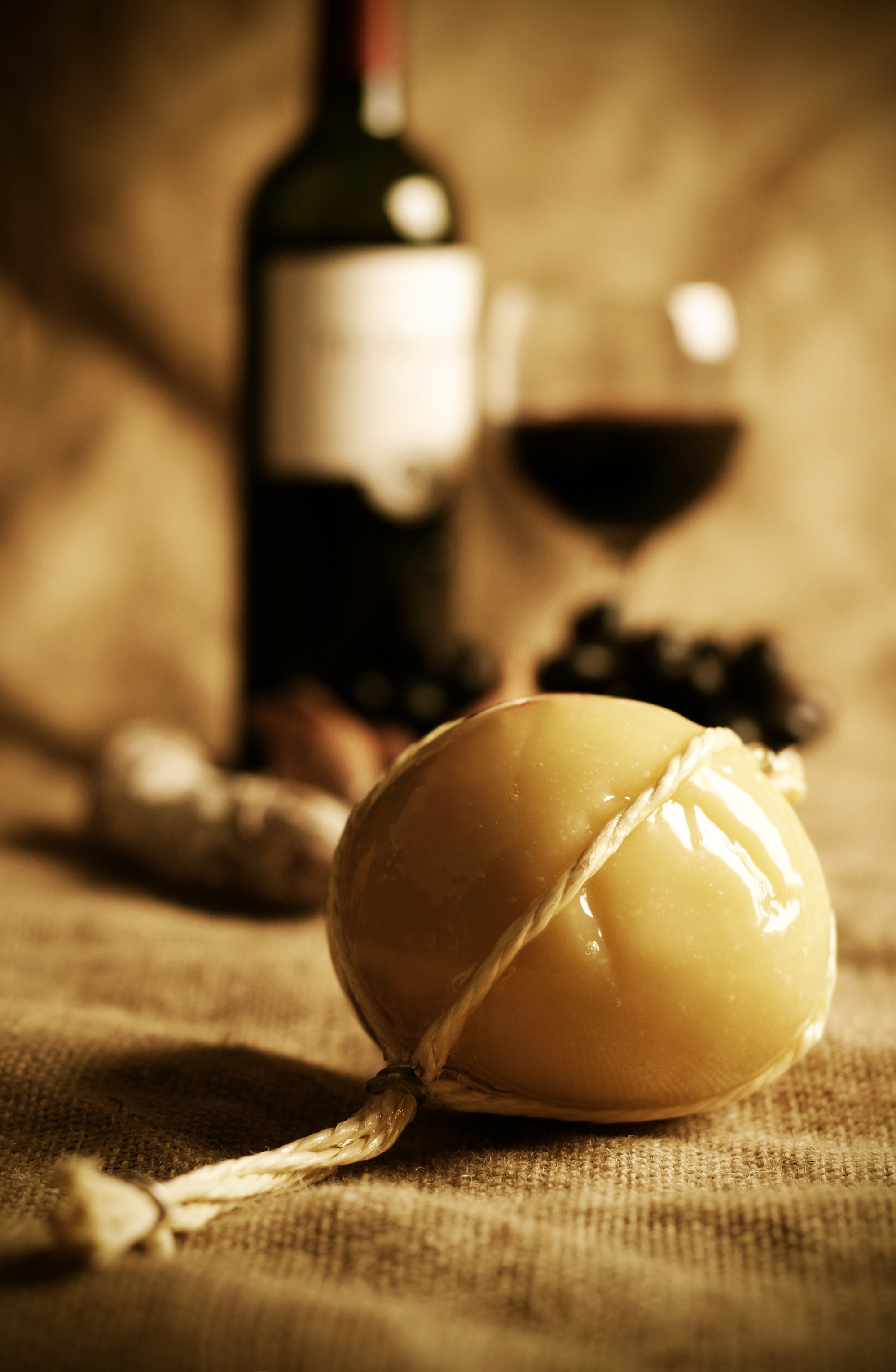 Ball of traditional provolone cheese with red wine, grapes, & saucisson in background (Foto: Getty Images)
