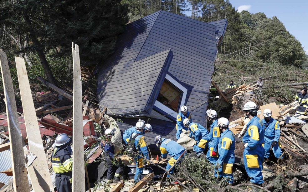 Equipes de resgate procuram sobreviventes de uma casa danificada cidade de Atsuma (Foto: Kyodo / via Reuters)