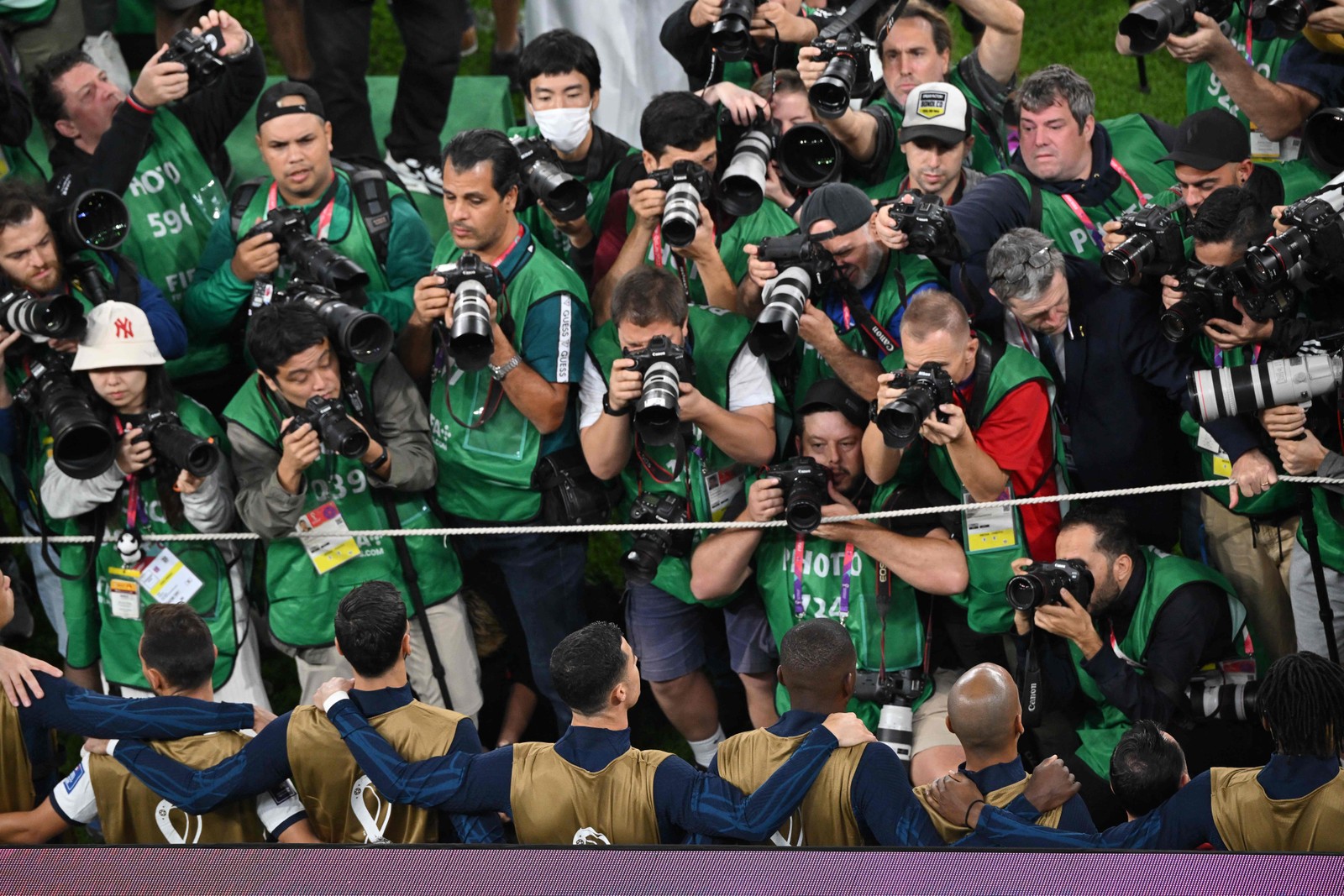 Com Cristiano Ronaldo (de costas, ao centro) no banco, fotógrafos se aglomeram diante do craque de português durante o hino nacional — Foto: Nelson Almeida/AFP