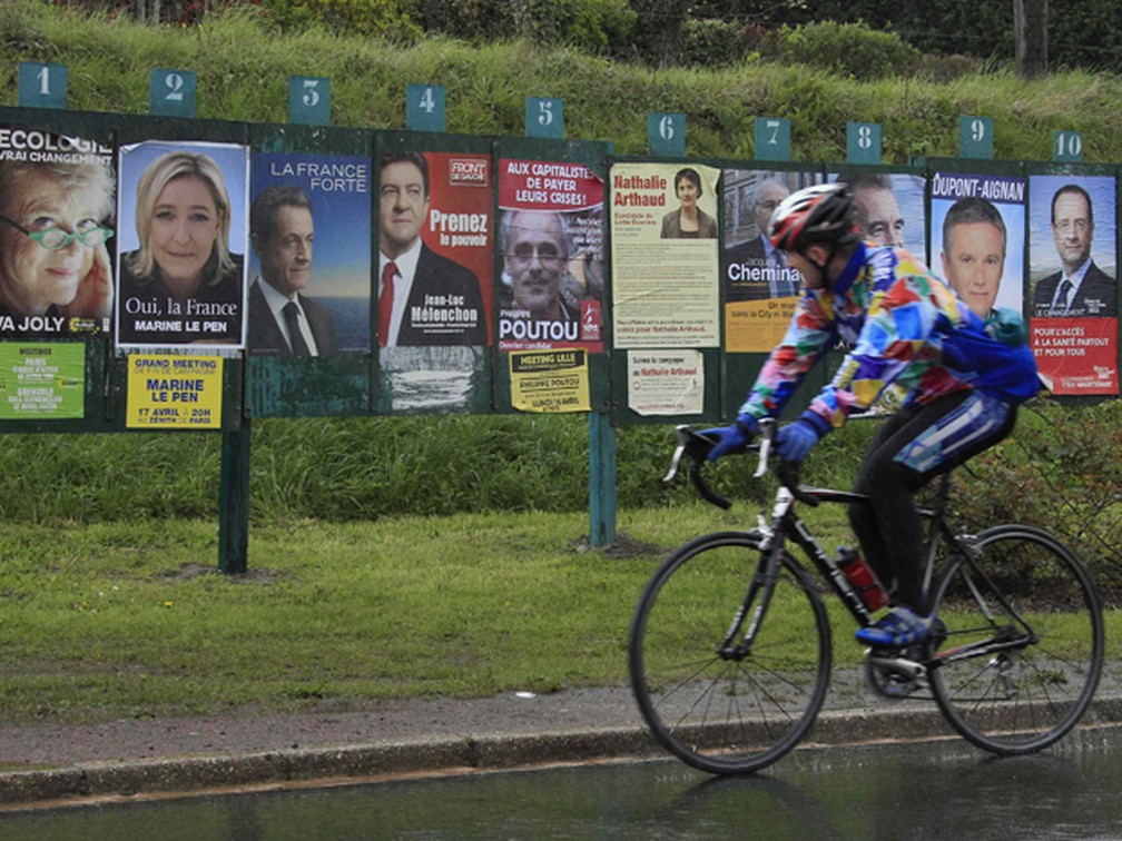 Ciclista passa em frente a painel com cartazes de candidatos à presidência da França,perto de Lille (Foto: Reuters)