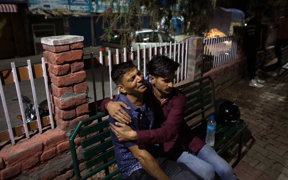 Pai chora e é consolado após saber da morte de seu filho em acidente com ônibus escolar a cerca de 60 km ao sul de Dharmsala, na Índia, na segunda-feira (9) (Foto: AP Photo/Ashwini Bhatia)