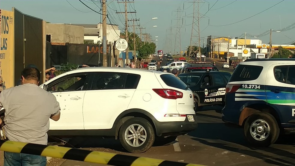 Carro em que estava a v&Atilde;&shy;tima ficou com marcas de tiros; pol&Atilde;&shy;cia no local em MS (Foto: Fabiano Arruda/ TV Morena)