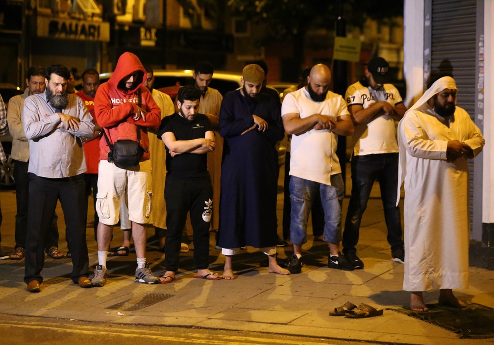 Homens oram após motorista atropelar pessoas em frente a mesquita em Finsbury Park, no norte de Londres — Foto: Neil Hall/Reuters