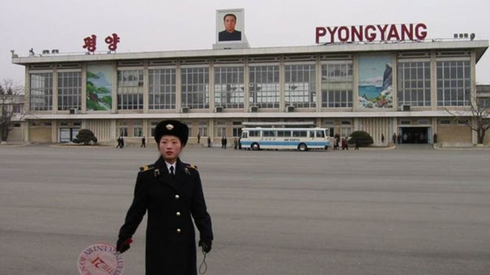 No Aeroporto Internacional Sunan, de Pyongyang, uma guarda leva uma placa que diz: 'O Sol do Século XXI', em homenagem a Kim Jong Il (Foto: Cortesia Suki Kim)