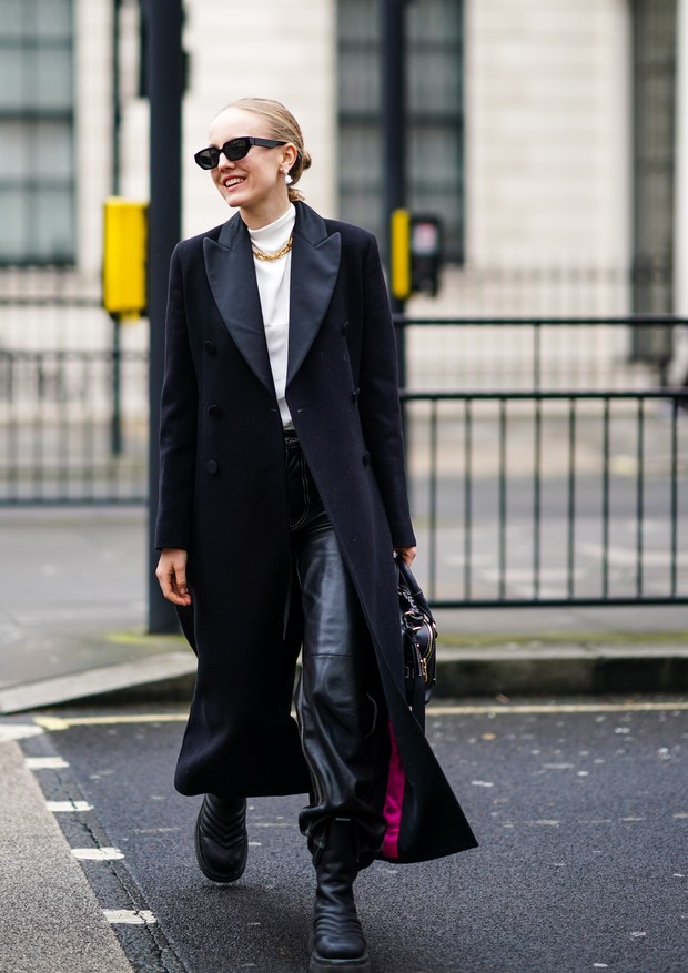 LONDON, ENGLAND - FEBRUARY 15: A guest wears sunglasses, earrings, a golden chain necklace, a white turtleneck pullover, a black long coat, black leather pants, leather boots, during London Fashion Week Fall Winter 2020, on February 15, 2020 in London, En (Foto: Getty Images)