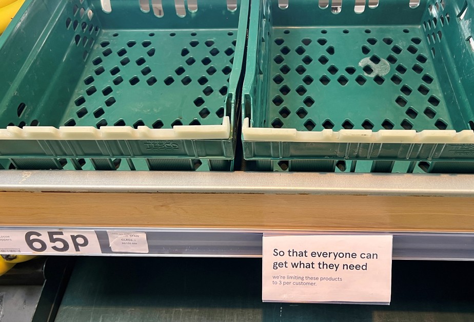 Um aviso limitando os clientes a três itens cada é visto ao lado de caixas vazias na seção de tomates e pimentões de um supermercado Tesco, em Manchester, Reino Unido