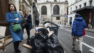 Pessoas passam por lixo não coletado em Paris, em 13 de março de 2023 — Foto: Lewis Joly/AP