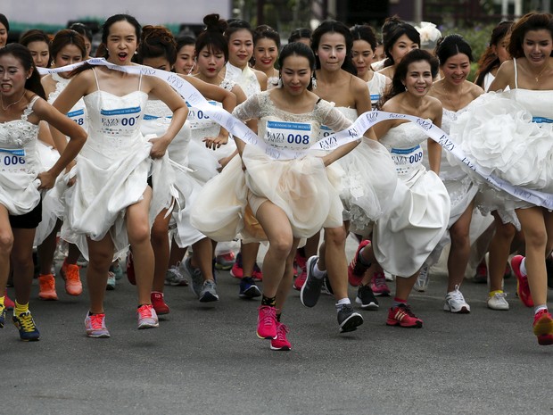 Centenas de noivas e noivos participaram neste sábado (28) de uma corrida temática em Bangcoc, na Tailândia, na qual os casais perto de se casarem precisam correr vestidos com as roupas da festa de casamento e tênis de corrida (Foto: Athit Perawongmetha/Reuters)