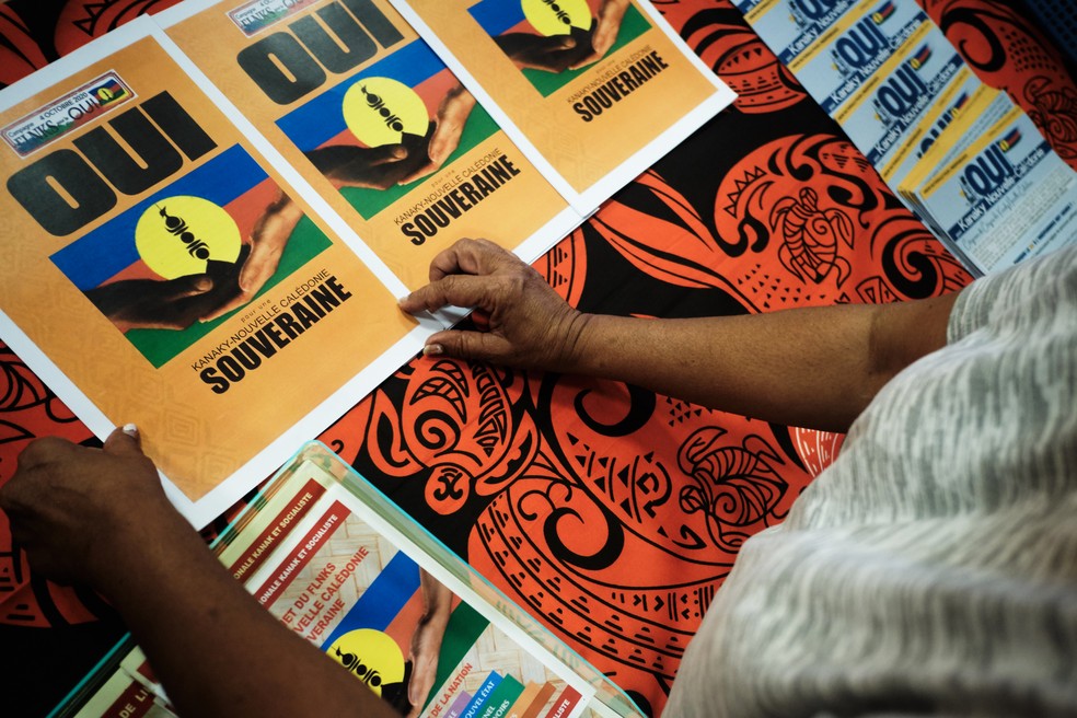Apoiante prepara cartazes pelo "sim" no referendo durante reunião sobre o futuro da Nova Caledônia em Kone, na segunda-feira (28)  — Foto: Theo Rouby/AFP