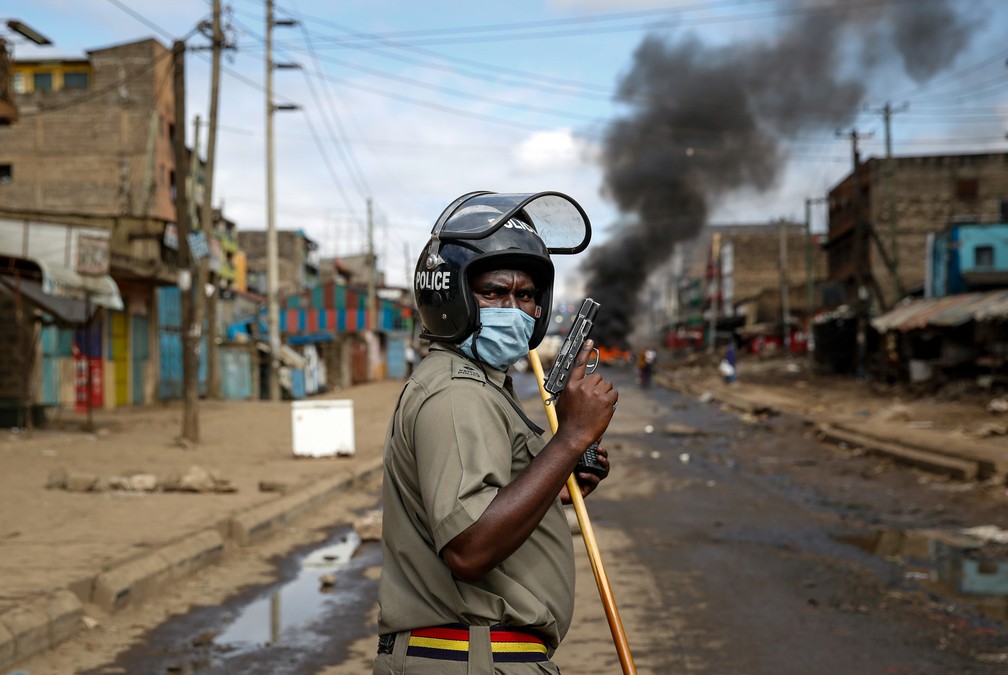 8 de maio - Um policial segura uma pistola durante confrontos com manifestantes perto de uma barricada de pneus queimados na favela Kariobangi de Nairóbi, no Quênia. Centenas de manifestantes bloquearam uma das principais rodovias da capital para protestar contra as demolições feitas pelo governo das casas de mais de 7 mil pessoas — Foto: Brian Inganga/AP