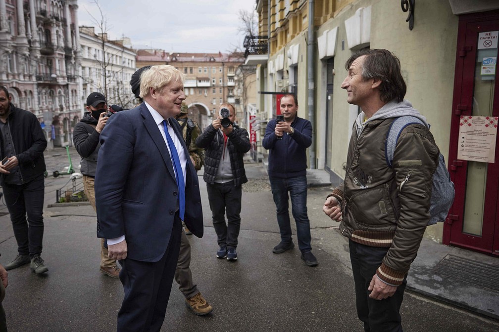Johnson fala com transeunte durante sua caminhada pelas ruas do centro de Kiev neste sábado (9). — Foto: ASSOCIATED PRESS