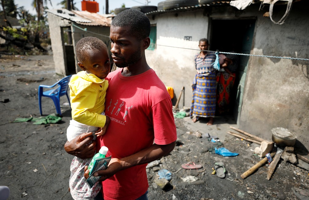 Nelson Vasco, morador de Beira, com a filha do lado de fora de casa. — Foto: Reuters/Mike Hutchings TPX Images of the Day