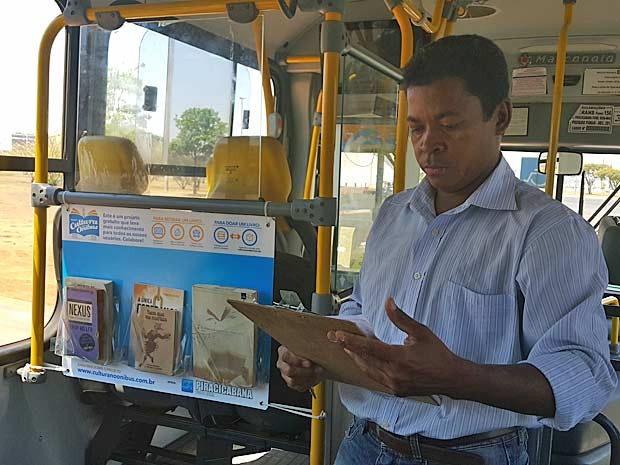O cobrador Antônio Freitas, ao lado de 'estante' montada em ônibus do DF para receber livros (Foto: Raquel Morais/G1)
