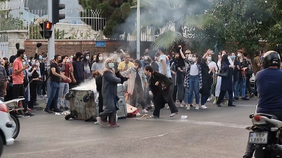 Esta captura tirada de um vídeo e datada de 22 de setembro de 2022 mostra manifestantes iranianos queimando seus lenços na cabeça e incendiando uma lixeira na capital Teerã.