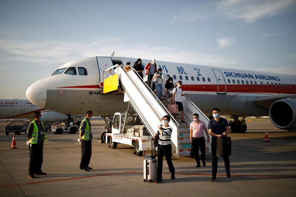 Passageiros que usam máscaras protetoras deixam uma aeronave da Sichuan Airlines no Aeroporto Internacional de Pequim, na China, nesta terça-feira (16)  — Foto: Carlos Garcia Rawlins/ Reuters
