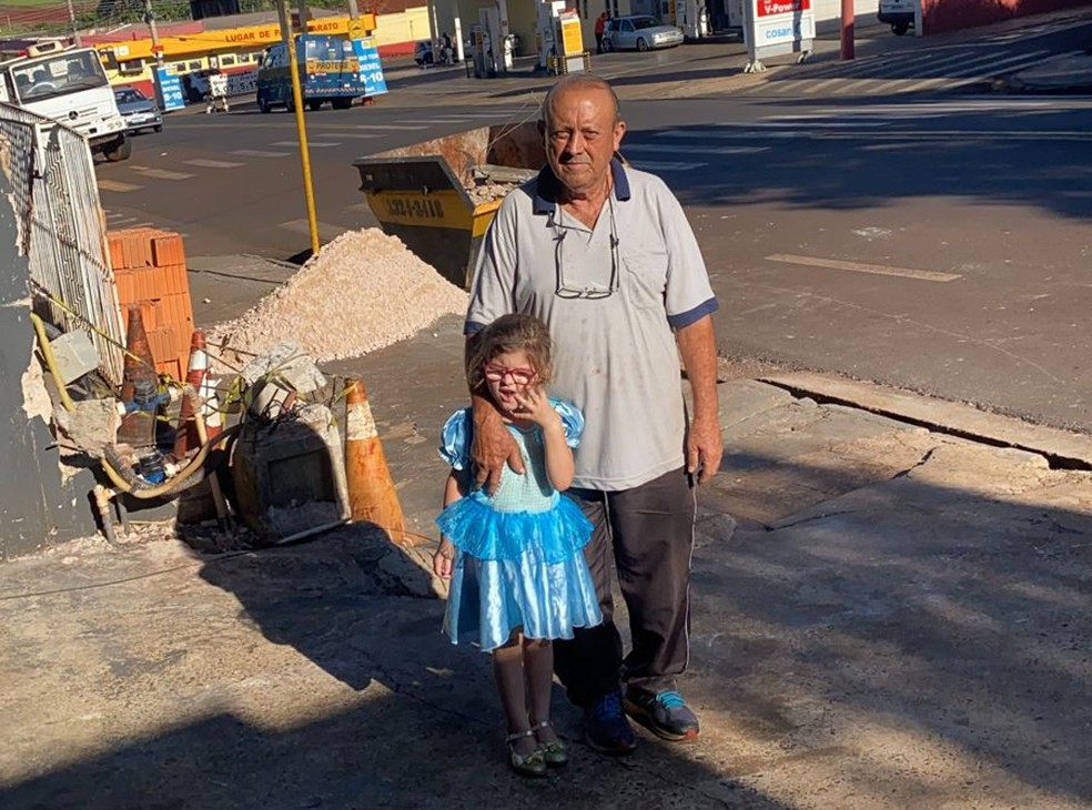 O comerciante Sérgio Moreira com a pequena Sara em frente aos destroços deixados pelo caminhão desgovernado: "Foi por Deus" — Foto: Arquivo pessoal