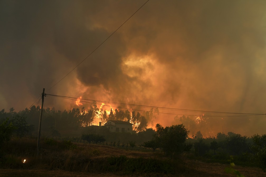 Incêndio florestal atinge uma casa na aldeia de Bemposta, perto de Ansião, no centro de Portugal, na quarta-feira (13). Milhares de bombeiros continuam a combater incêndios em todo o país, que forçaram a saída de dezenas de pessoas das suas casas.  — Foto: Armando Franca/AP