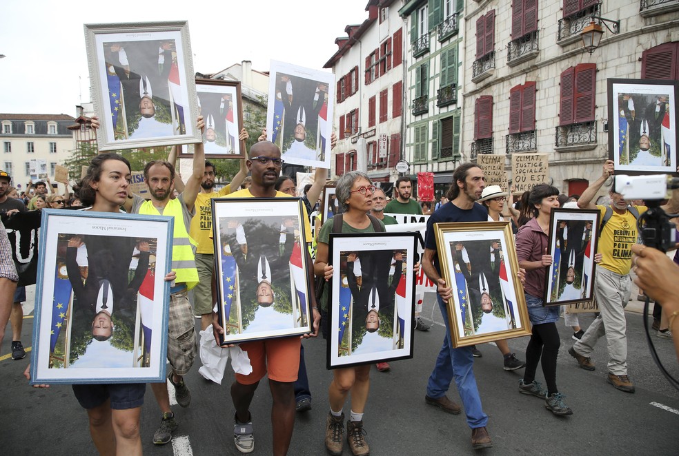 Manifestantes carregam retratos de cabeça para baixo do presidente francês Emmanuel Macron durante protesto pelas ruas de Bayonne, na França, neste domingo (25) — Foto: Bob Edme/AP