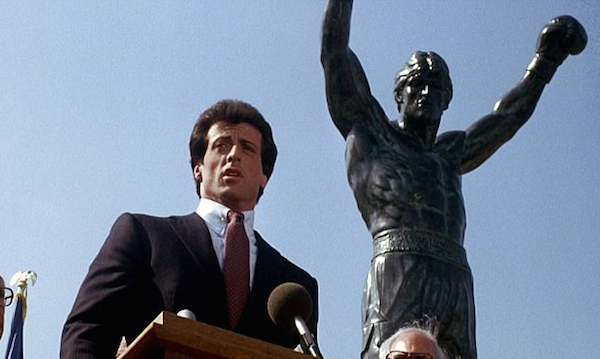 O ator Sylvester Stallone em cena de Rocky III na qual aparece em frente à estátua do boxeador na Filadélfia  (Foto: Reprodução)